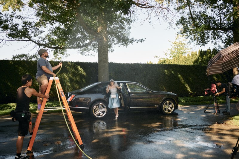 Boom operator holding a microphone above a scene in progress.