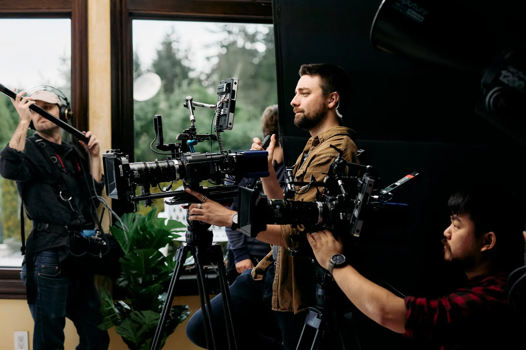 A film crew at work on location in Vancouver, the camera operator framing a shot while the boom operator holds the microphone overhead.