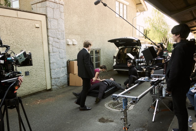 Crew setting up lighting and reflectors for an outdoor shot.