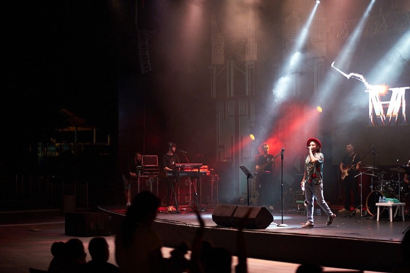 Stage lighting rig casting beams across a darkened venue.