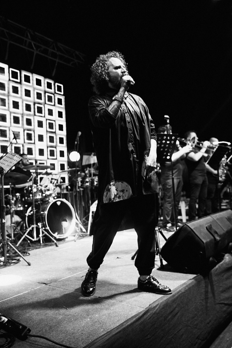 Singer at the microphone under coloured stage lighting.