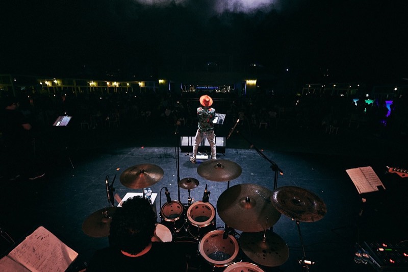 Musician lit from behind by stage wash, in silhouette.