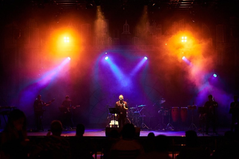 Singer at the microphone under coloured stage lighting.