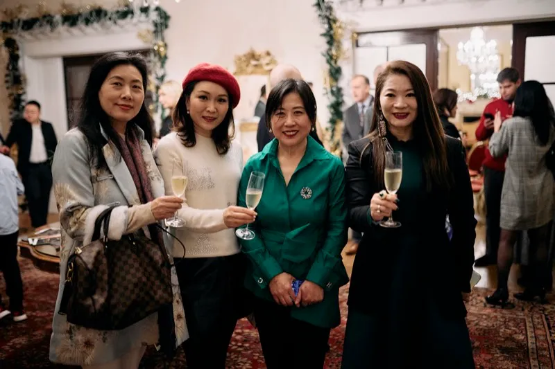 Four guests raise champagne flutes for a photograph under Christmas garlands.