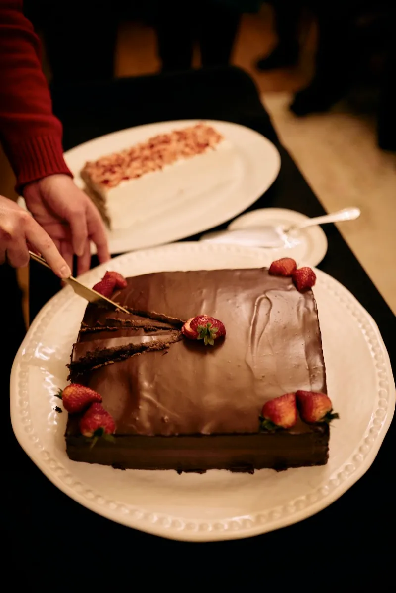 A slice being cut from a chocolate cake topped with strawberries.
