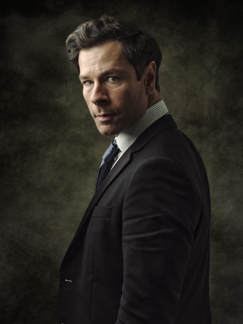 Professional portrait lit with a single soft key light, shoulders square to camera.