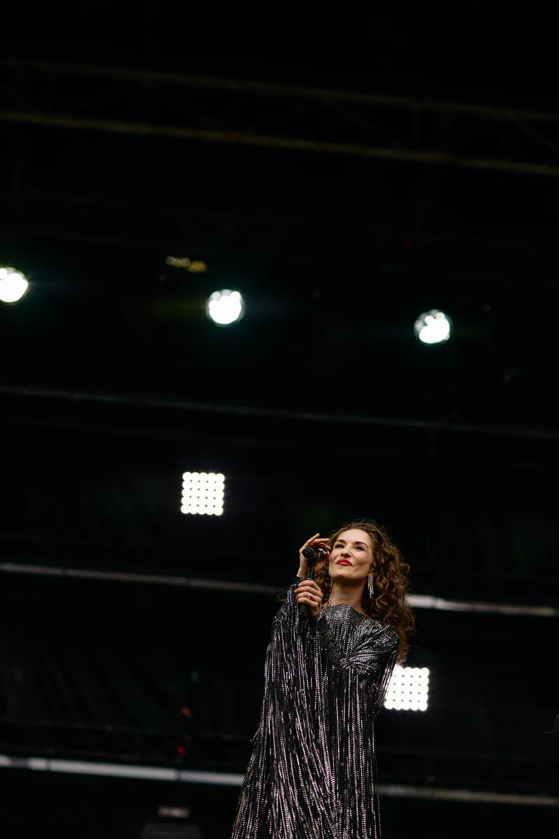 MAKENZA alone at the microphone under a single stage light, upright frame.