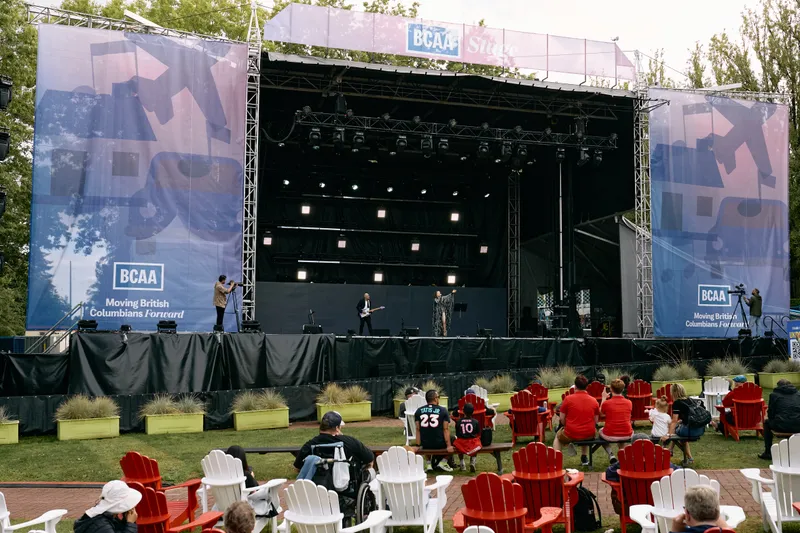The BCAA Stage seen from the lawn before the set, crew on stage and the red and white chairs filling up.