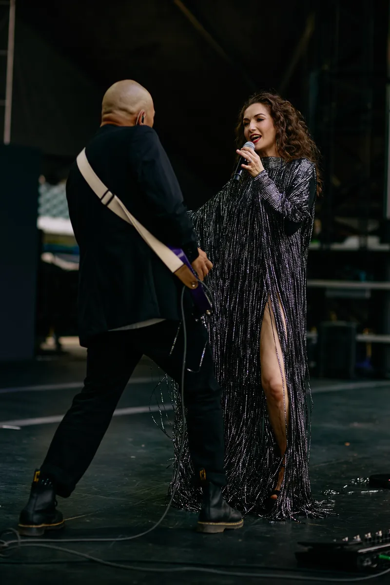 The singer and the guitarist face each other at the front of the stage.