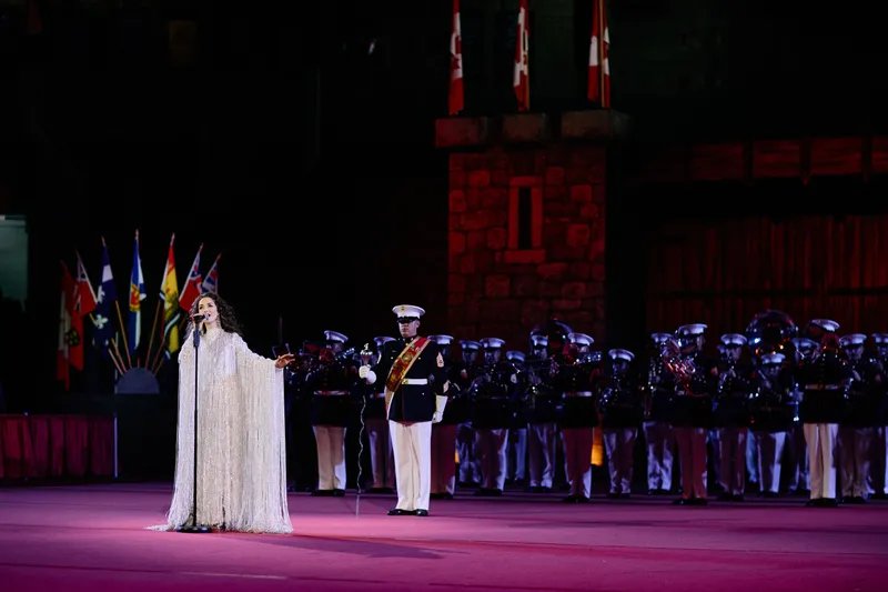 MAKENZA in a long white dress sings with the band standing behind her.