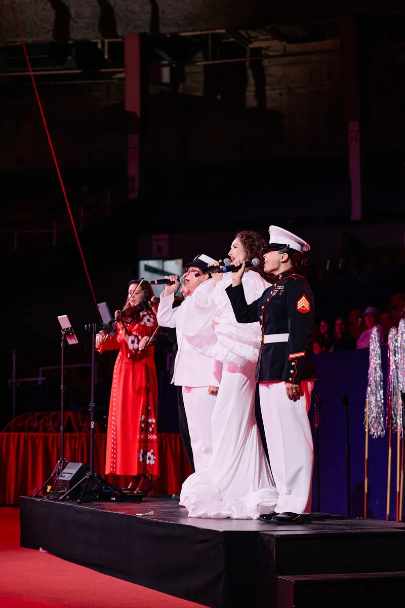 MAKENZA sings from the riser between the officers at the finale.
