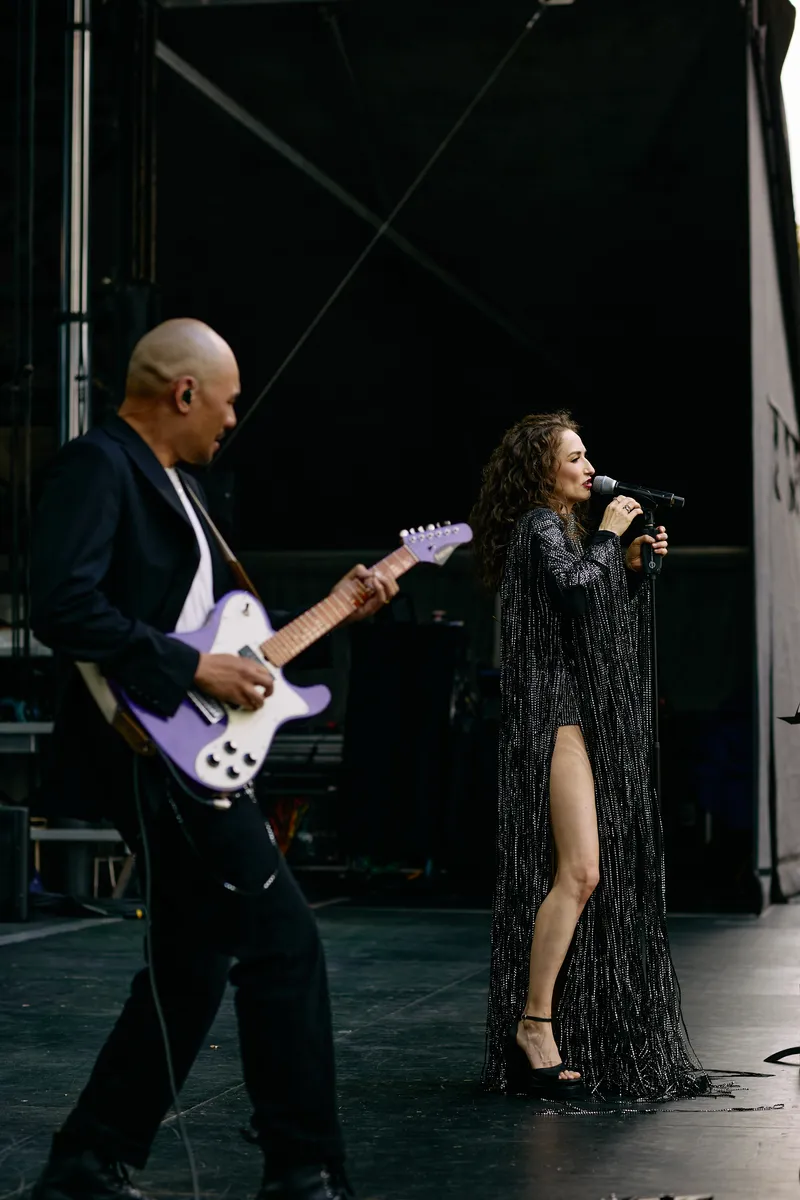 MAKENZA at the microphone beside the guitarist and his pale purple guitar, upright frame.