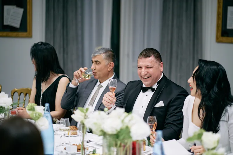 A guest raises his glass in a toast across the dinner table.