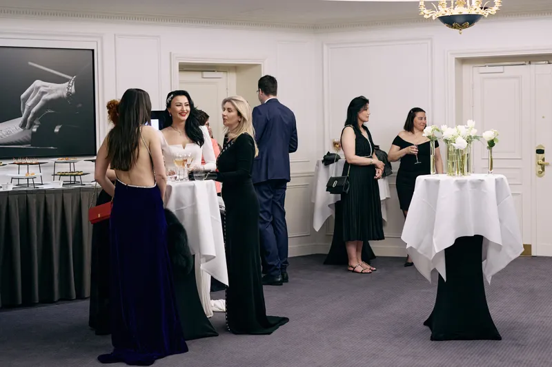 Guests in evening wear stand in small groups across the reception room.