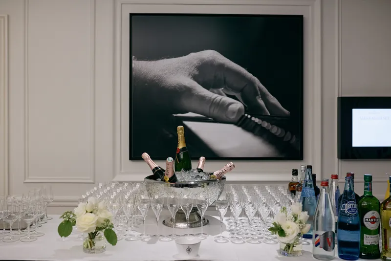 The bar with champagne, bottled water and white flowers, a framed black and white photograph on the wall above.