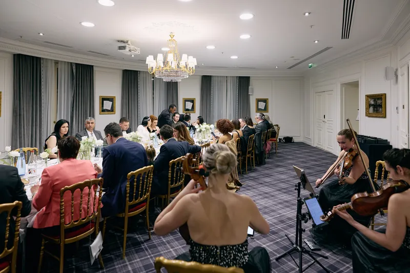 Guests at dinner with the musicians playing at the far end of the room.