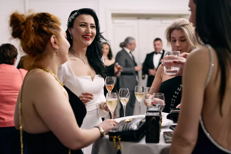 Guests laugh with the bride at a cocktail table, glasses raised.