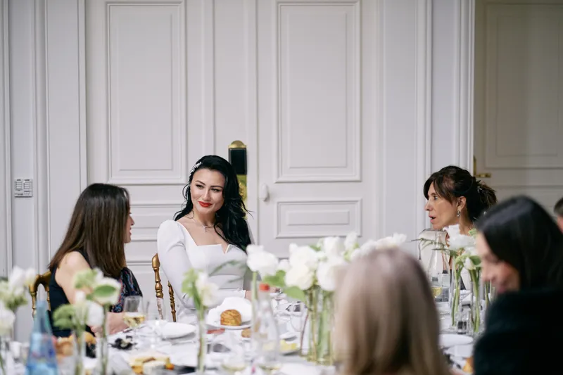 Julie at the table among her guests, smiling.