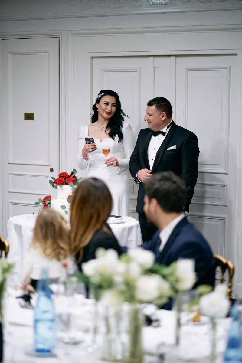 Michael and Julie listen together, a glass each, red roses on the table in front of them.