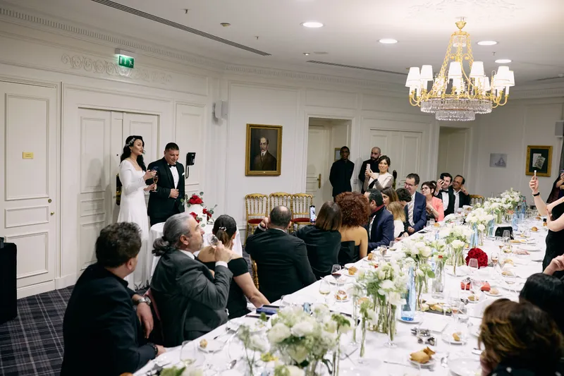 The whole room at dinner, the long table full and the chandelier lit.