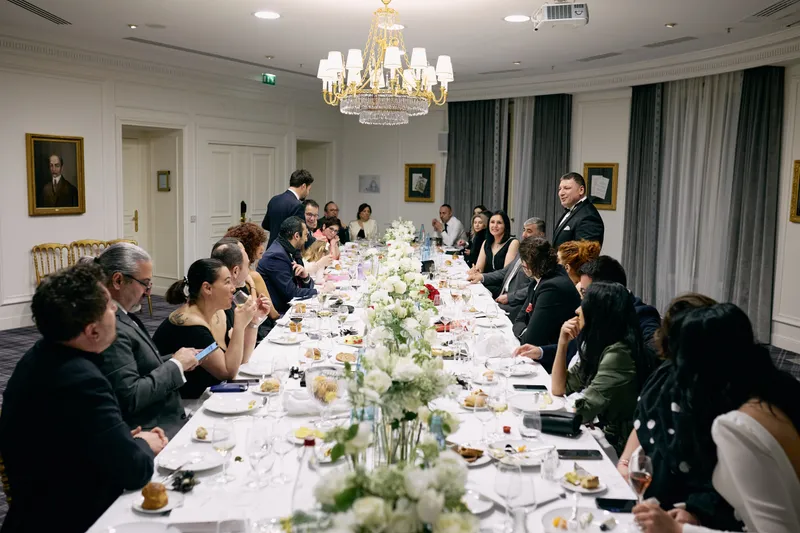 The full length of the reception table from one end at the end of the evening, guests seated along both sides beneath the chandelier.