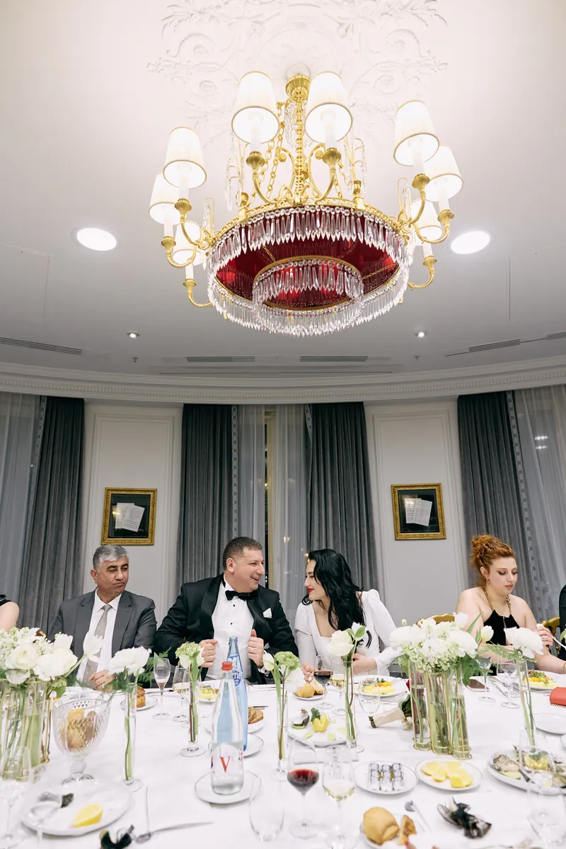 The crystal chandelier glowing above the guests at dinner.