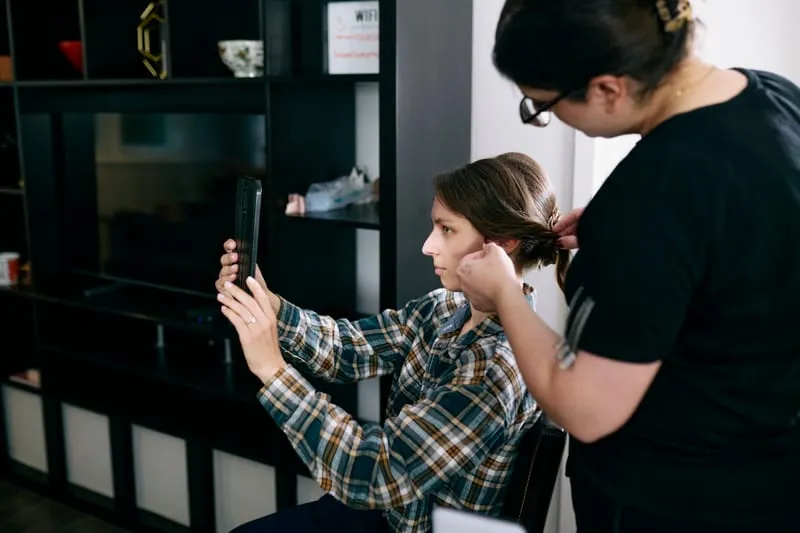 A hair stylist at work while family talk in the living room.