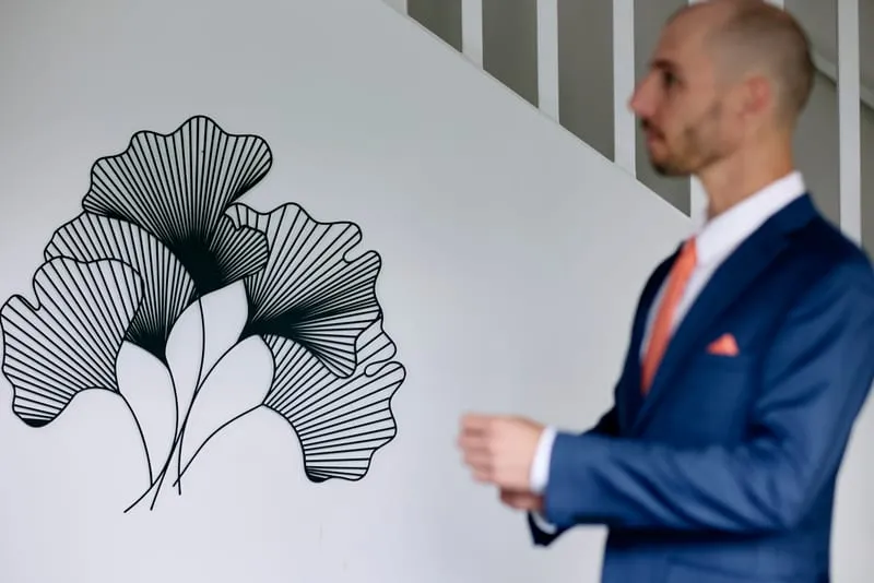James in his blue suit beside a ginkgo-leaf mural, buttoning his jacket.