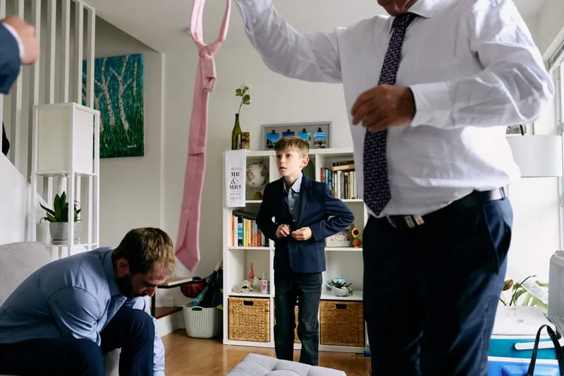 A small boy in a suit and tie, ready before everyone else.