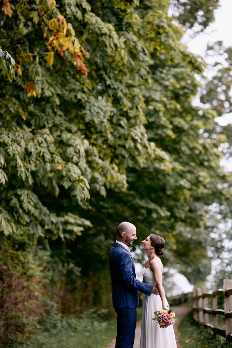 A kiss under the trees, bouquet in hand.