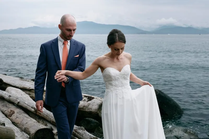 Olivia lifting her dress over the logs, James holding her hand.