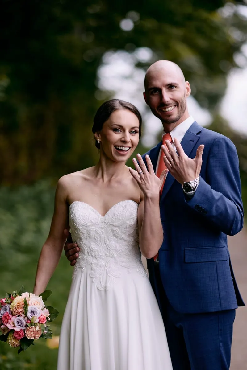 Olivia and James showing their rings, both grinning.