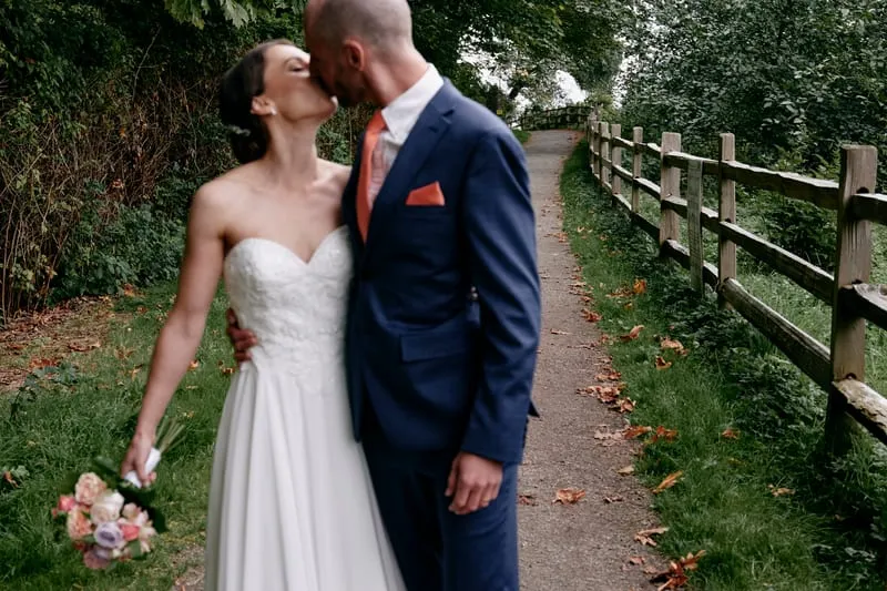 A kiss by the fence, the bouquet at her side.