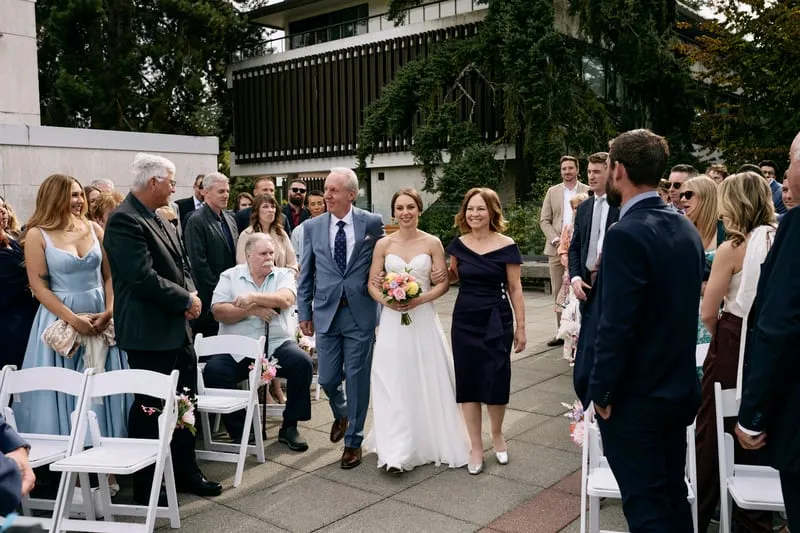 Olivia walking down the aisle between her parents.