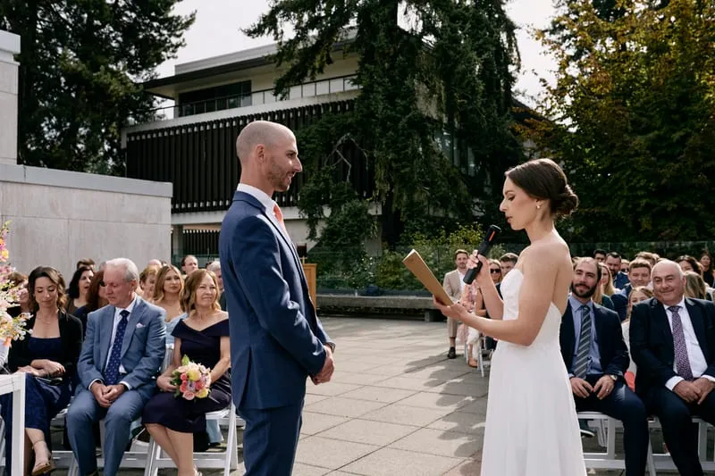 James listening as Olivia reads, guests behind them.