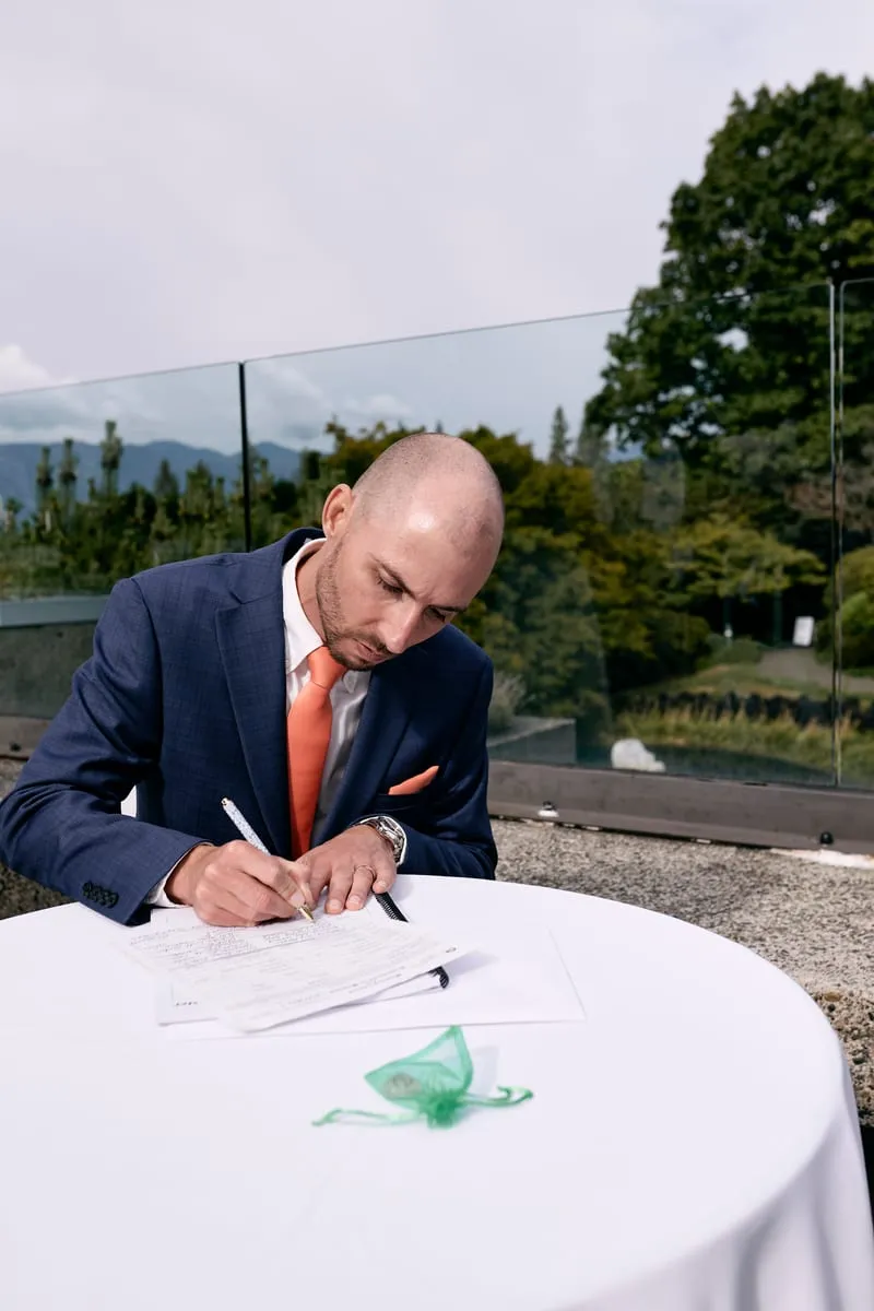 James signing the register at a small white table.