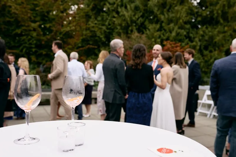 Glasses on a white table on the terrace, guests beyond.