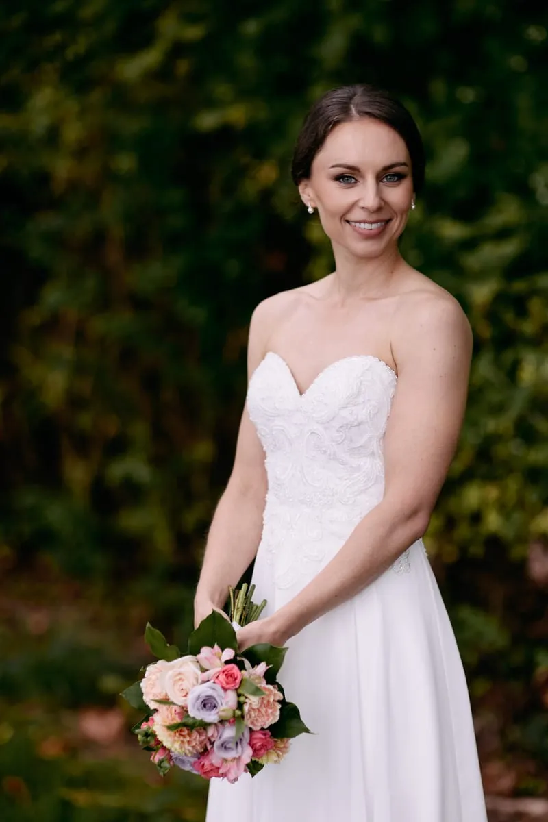 Olivia smiles at the camera, her bouquet held low against her dress.