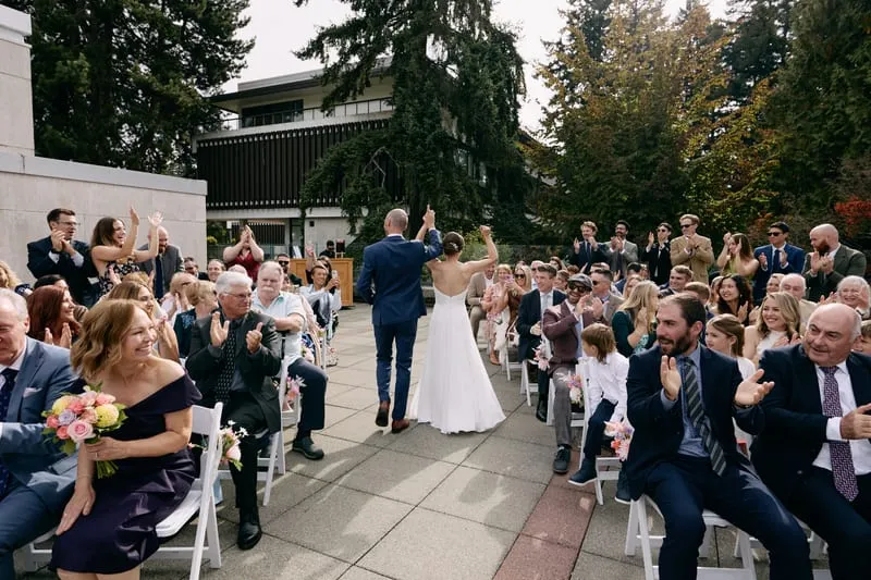 Olivia and James walk back down the aisle while the guests clap on both sides.