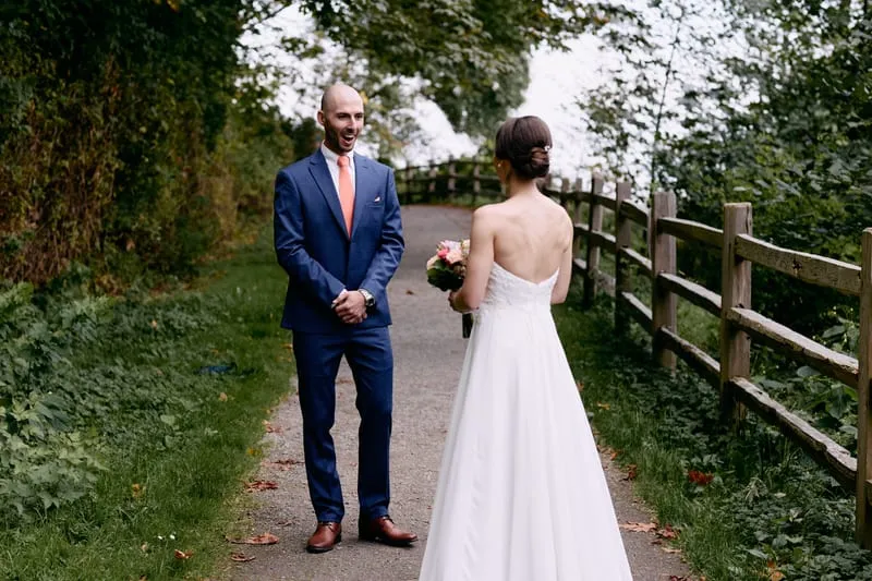 James turns and smiles at Olivia on the path, seen from just over her shoulder.