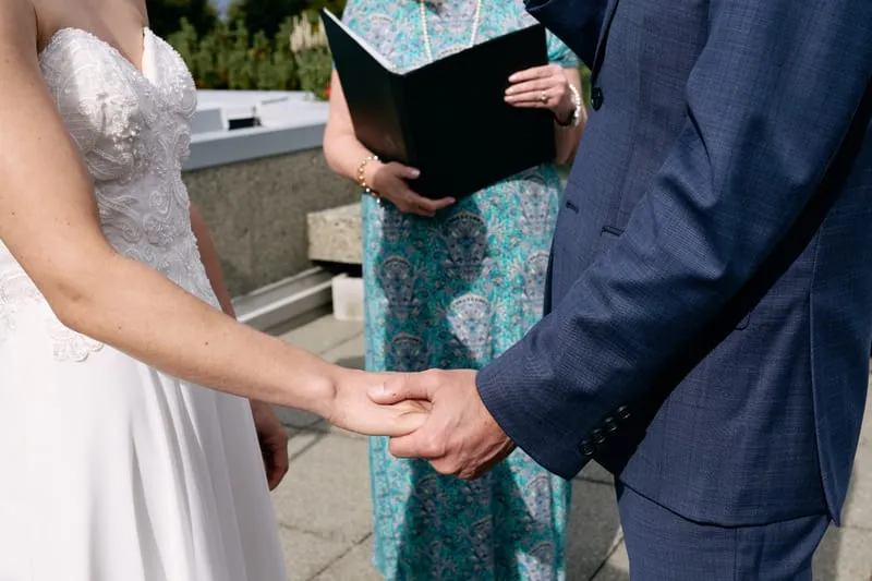 Olivia's and James's hands joined in front of the officiant's paisley dress.