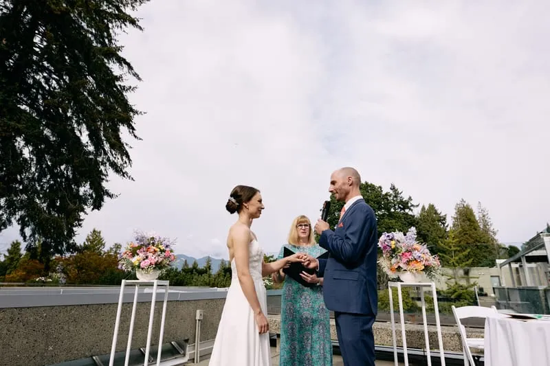 James speaks into the officiant's microphone as Olivia looks on.