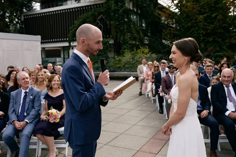 James reads his vows from a notebook while Olivia smiles back at him.