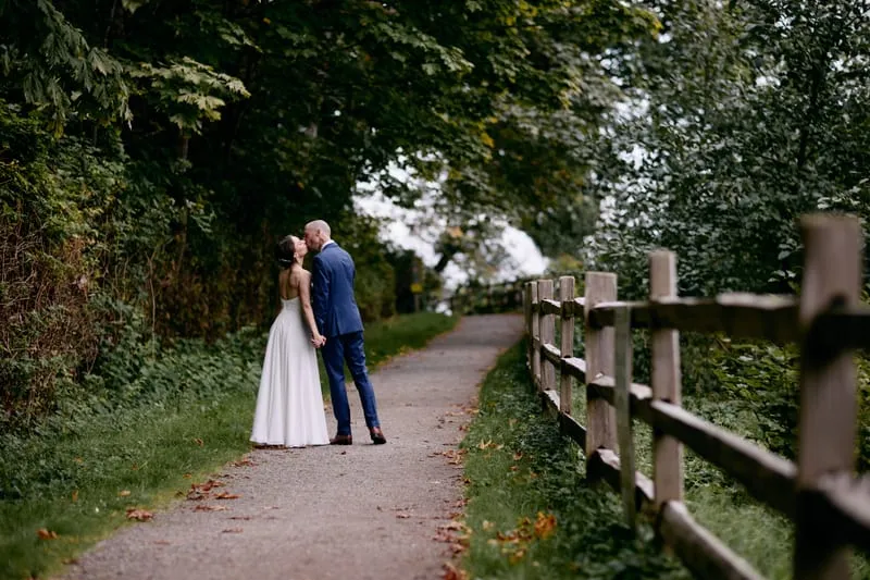 A small kiss far down a fenced path, framed by overhanging trees.