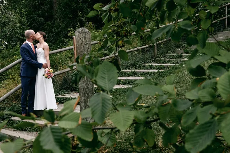A kiss on old wooden steps, half hidden behind alder leaves.