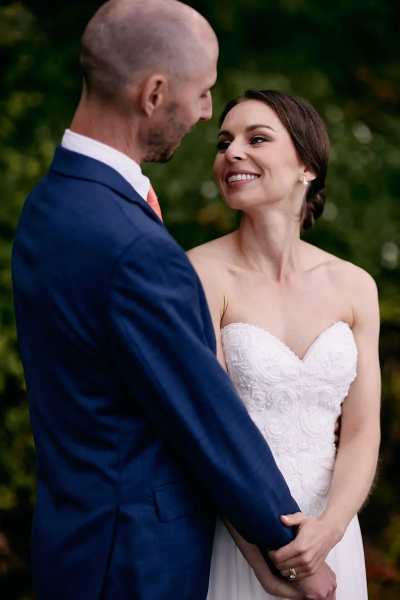 Olivia smiles up at James as he looks down at her, holding her hands.