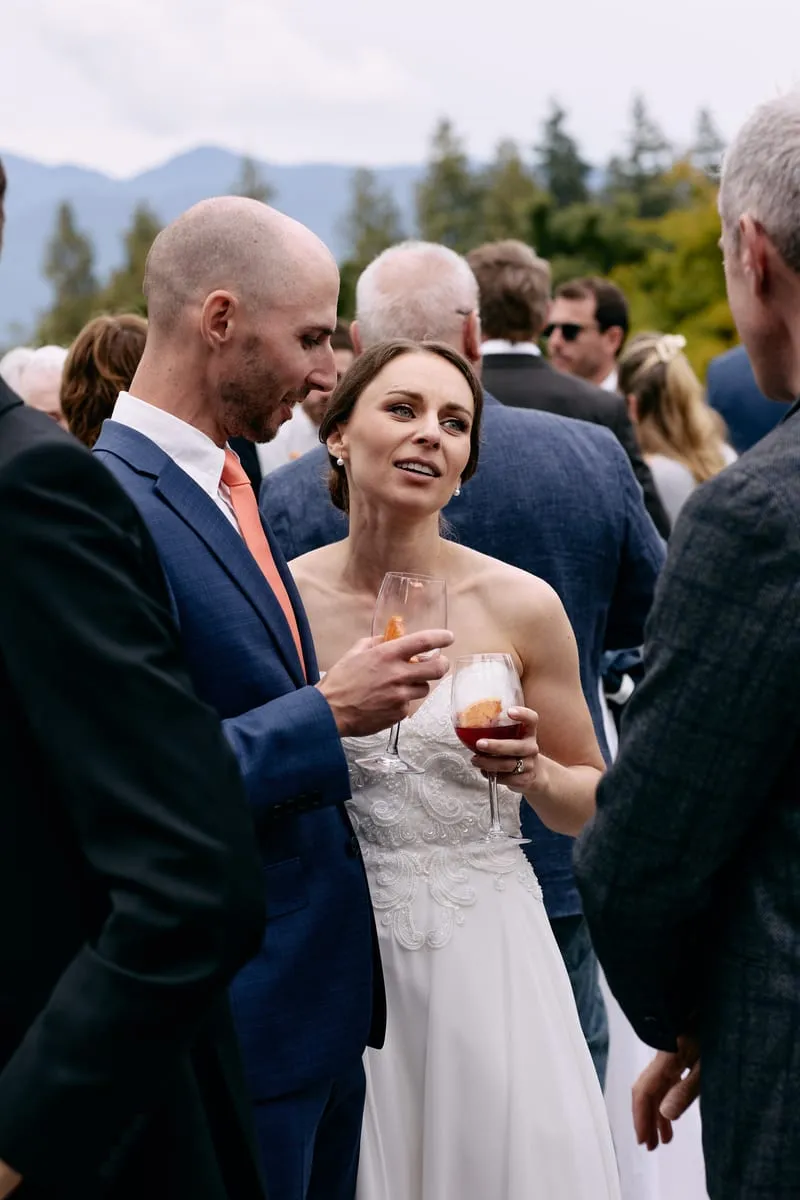 Olivia listens to a guest, a drink in her hand and James beside her.