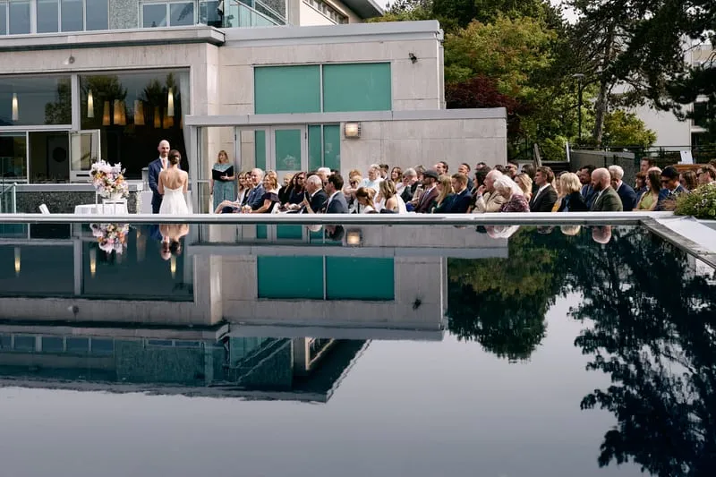 The whole ceremony reflected in the still water of the terrace pool.
