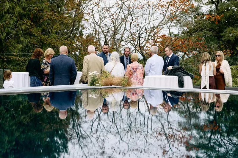 Guests and autumn trees reflected upside down in the terrace pool.