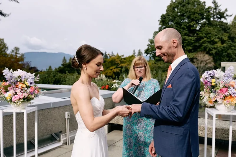 Olivia puts the ring on James's finger, both smiling down at their hands.